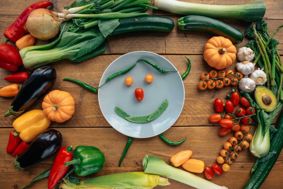 Verschiedene Gemüse um ein Gemüse-Smiley garniert.